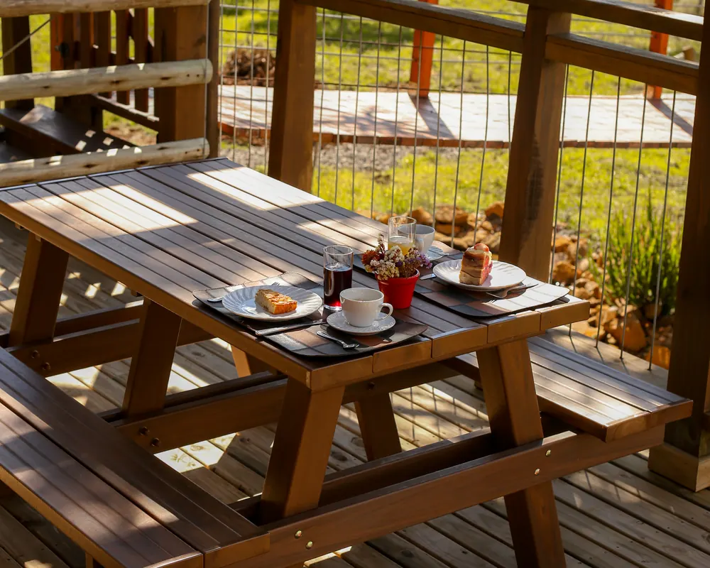Mesa de madeira no deck, com vista para as araucárias.