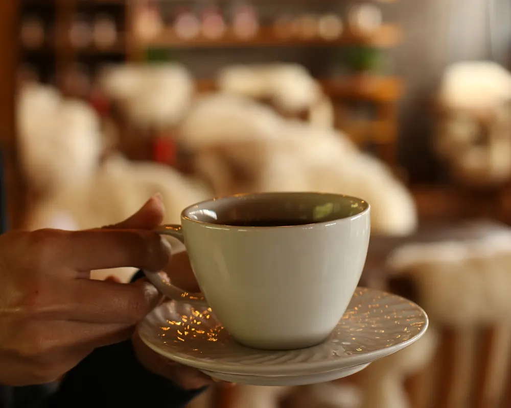 Detalhe da decoração: xícara de café diante das prateleiras do salão.
