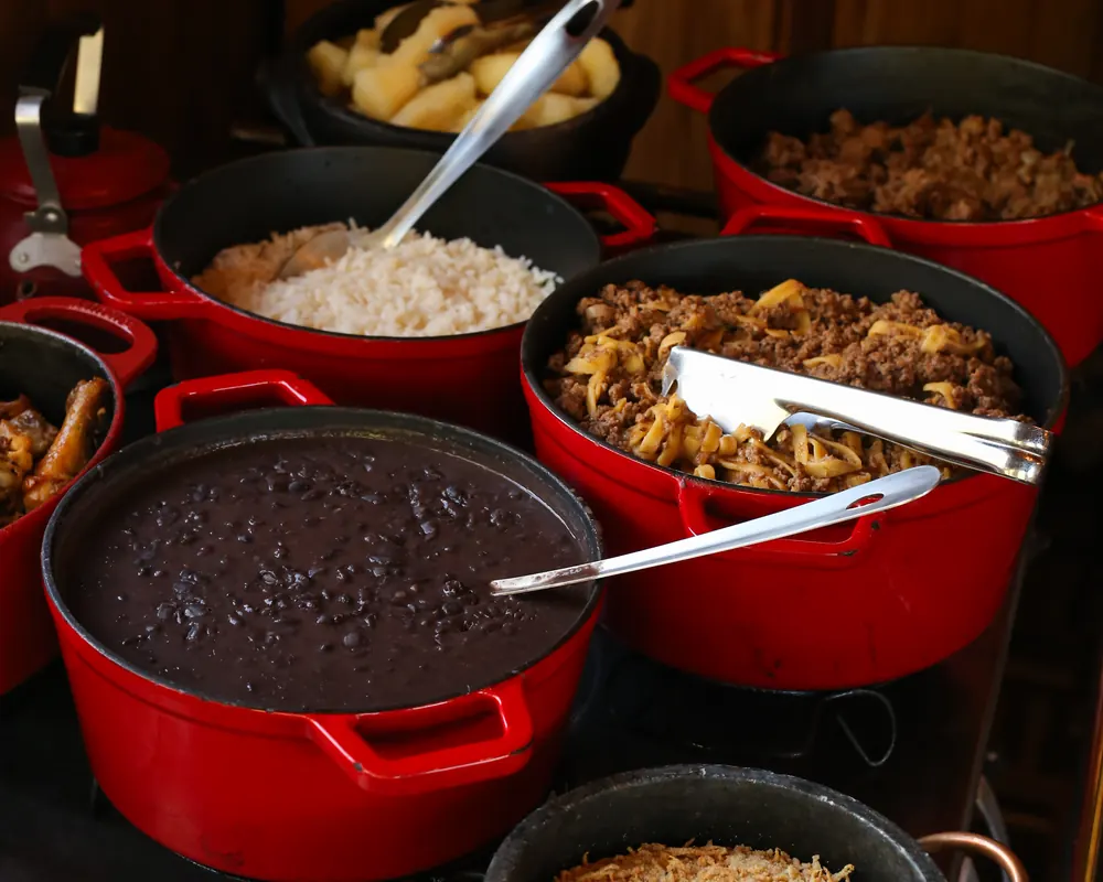Almoço caseiro em panelas sobre o fogão a lenha: arroz, feijão e carne.
