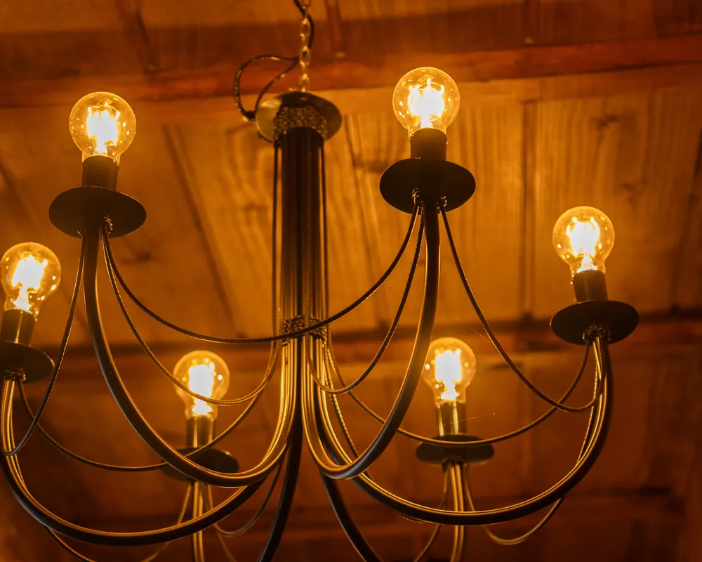 Lustre com lâmpadas de filamento sob o forro de madeira.