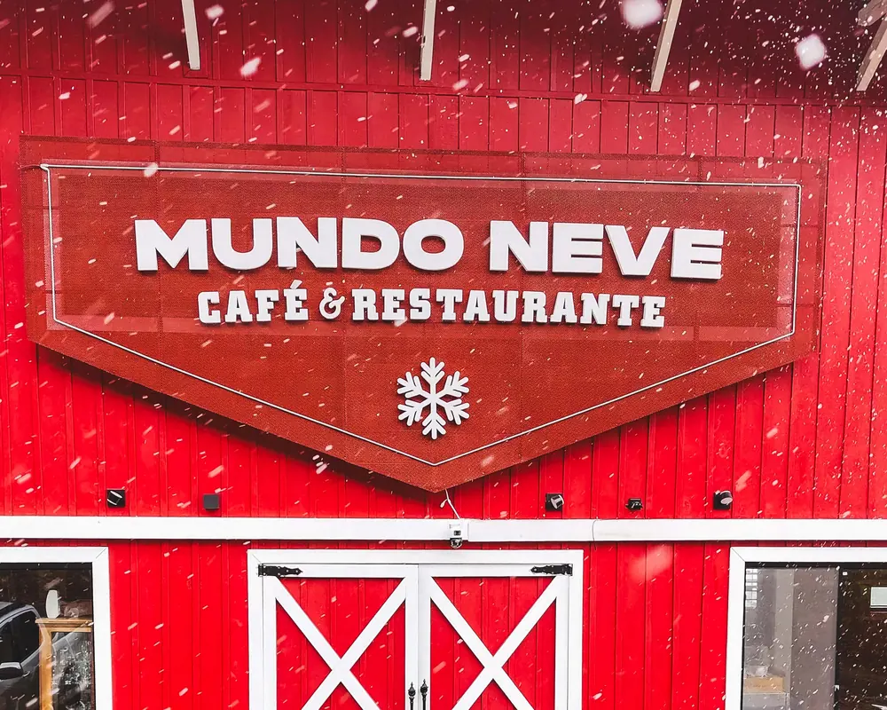 Fachada vermelha do Mundo Neve com neve caindo.
