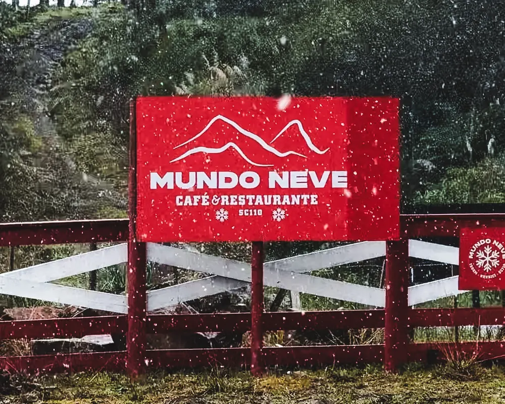 Placa do Mundo Neve na entrada, entre as araucárias.