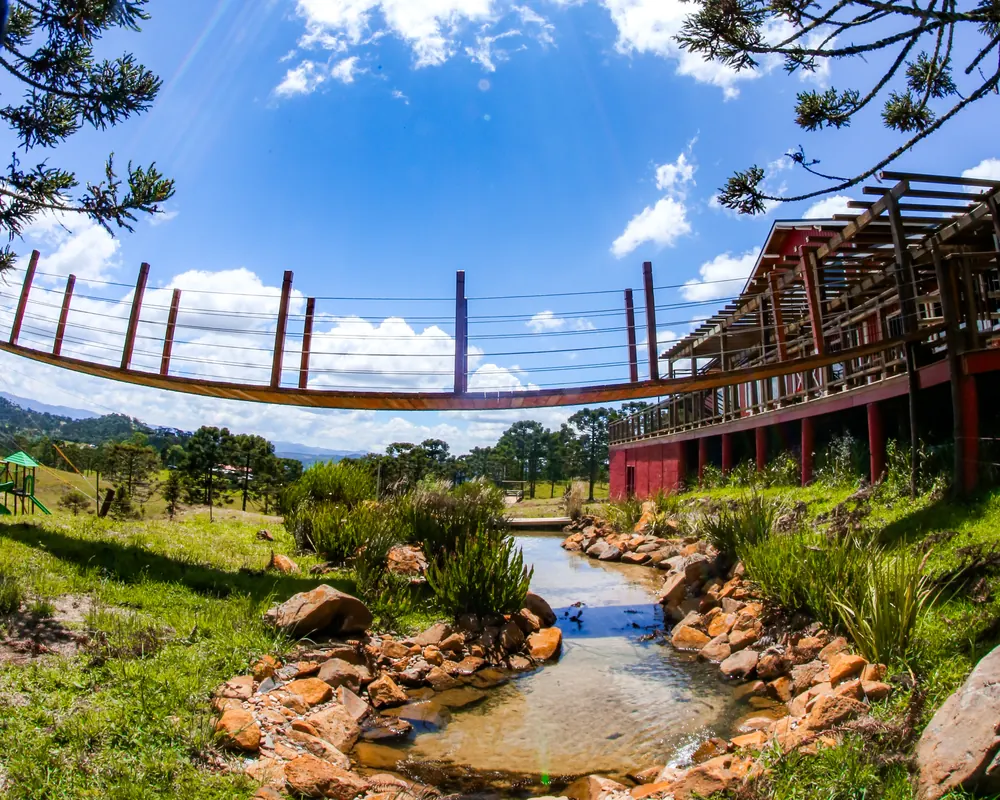 Riacho e ponte suspensa, com o restaurante ao fundo.
