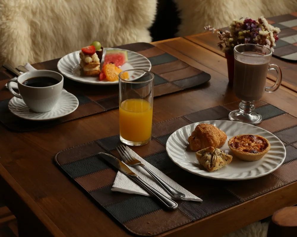 Mesa do salão com cadeiras de pelego, café e suco.