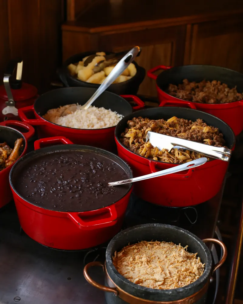 Panelas do almoço sobre o fogão a lenha: arroz, feijão e carne.