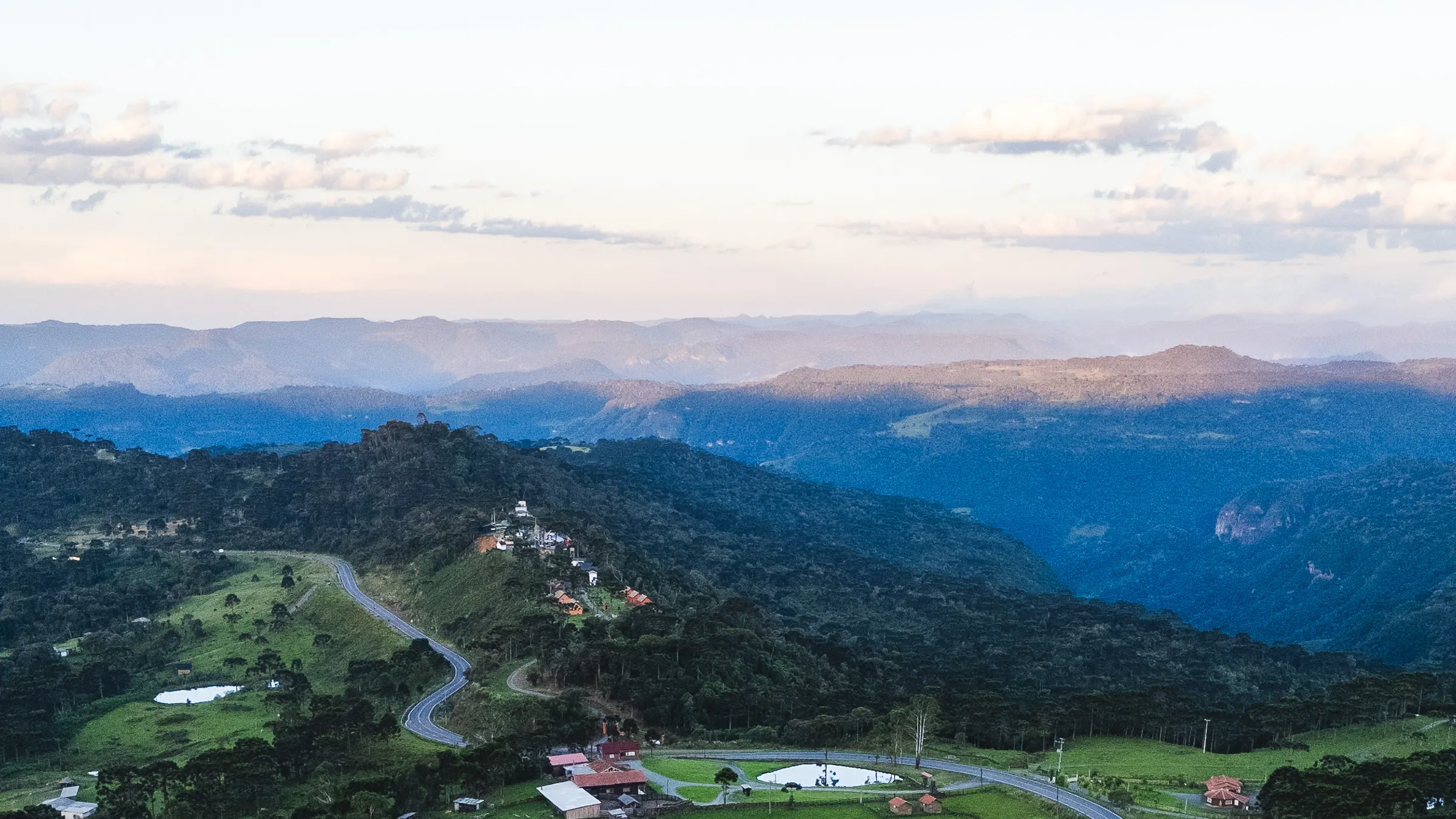 Vista panorâmica da Serra Catarinense ao entardecer, com montanhas até o horizonte.